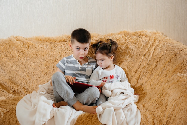 Fratello e sorella giocano sul divano del tablet.