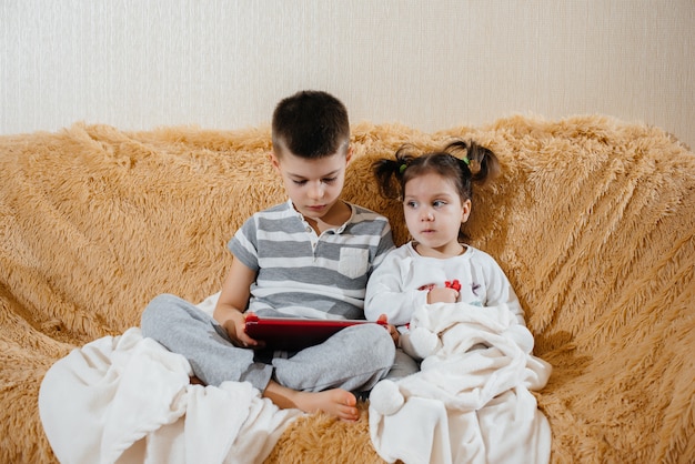 Fratello e sorella giocano sul divano del tablet.