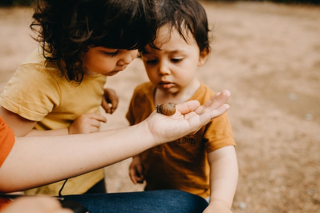 Fratello e sorella guardano la lumaca sulla mano della madre