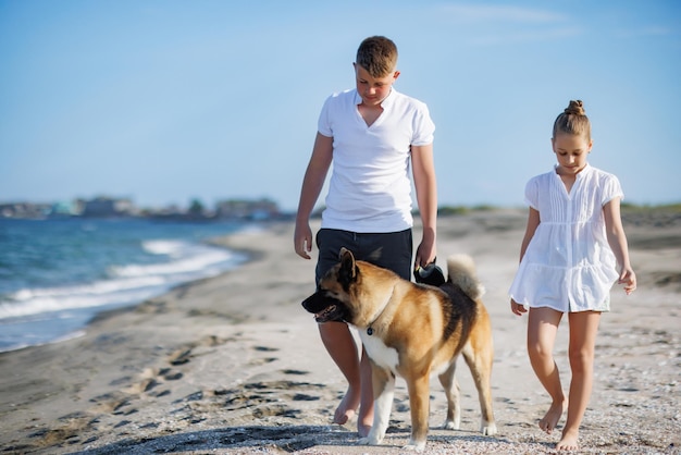 Fratello e sorella stanno camminando e con il cane di razza Akita Inu lungo la costa lungo il Mar Nero