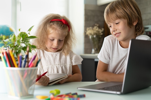 Fratello e sorella studiano a casa con bambini e gadget portatili