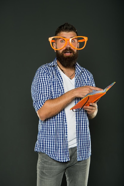 Freak e geek Uomo barbuto in occhiali da festa libro di lettura Studio nerd tenendo libro di lezione Studente universitario maschio con dispense Prenota nerd con occhiali fantasia