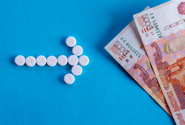 Freccia da pillole e denaro russo su sfondo blu Il concetto di bilancio medico di pagamento del trattamento di assicurazione sanitaria