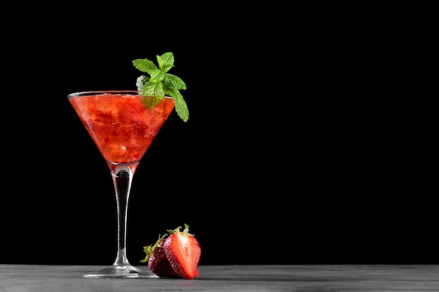 Fredda estate cocktail alla fragola mojito margarita daiquiri in un bicchiere da martini su sfondo nero da vicino