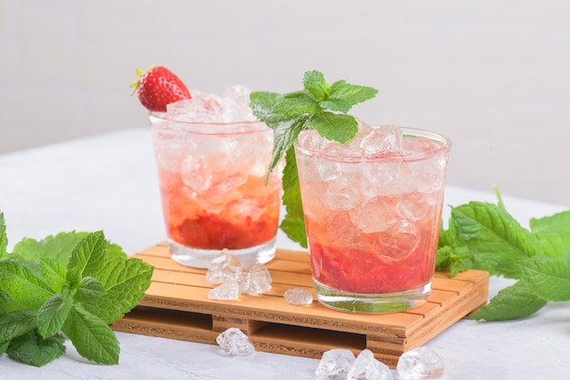 Fredda estate cocktail ghiacciato alla fragola mojito margarita daiquiri in due bicchieri con foglie di menta su sfondo chiaro