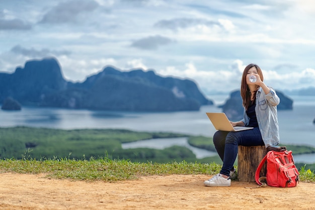 Free lance asiatiche della donna che lavorano con il computer portatile di tecnologia e che bevono l&#39;acqua a fantastico