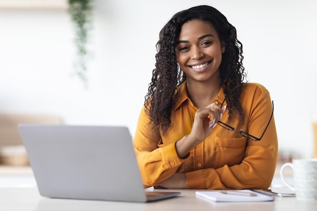 Freelancer abbastanza afroamericano della donna che utilizza il computer portatile a casa