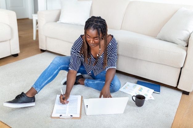 Freelancer positivo della giovane donna che guarda video nel blog sul netbook e che beve un caffè a casa comoda Bella giovane donna d'affari che lavora sul computer portatileFreelancer che si connette a Internet