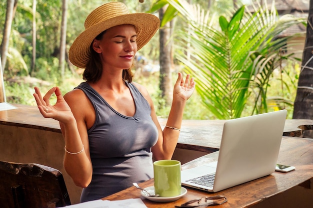 Freelancer Woman Work meditando e rilassandosi con il laptop in Tropical Cafe