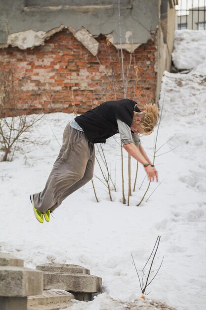 Freerun risolve adolescente capelli biondi ragazzo formazione parkour salto flip nel coperto di neve park