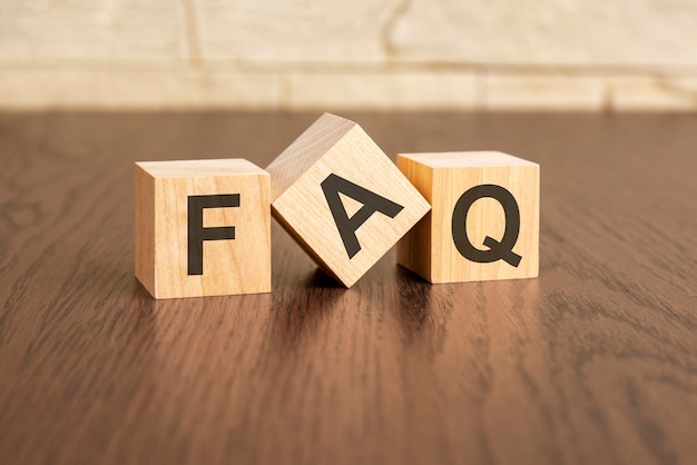 Frequency Asked Questions concept with symbols FAQ on wooden blocks dark wooden background