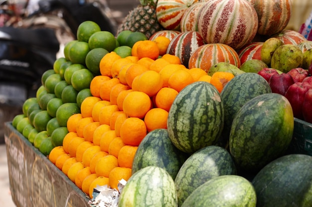 Freschi e locali Righe impilate di frutta fresca, lime, arance e meloni in un mercato indiano