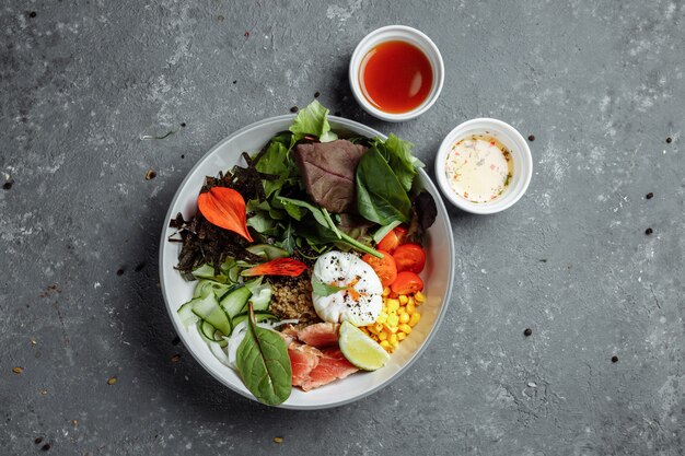 Fresco e salutare colazione leggera, pranzo di lavoro. Colazione con uovo in camicia, grano saraceno, pesce rosso, insalata fresca, cetrioli e pomodorini, concetto di pranzo di lavoro.