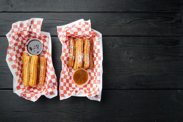 Fried Crullers in marrone, asporto in borsa nel vassoio della carta, su tavola in legno nero sfondo, vista dall'alto laici piatta con spazio per il testo, copyspace