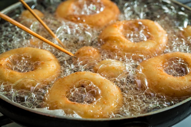 Friggere ciambelle dolci e gustose su olio fresco