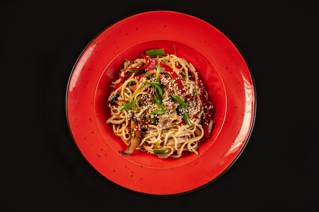 Friggere gli spaghetti con verdure e gamberetti in una ciotola nera Sfondo ardesia Vista dall'alto Spazio di copia