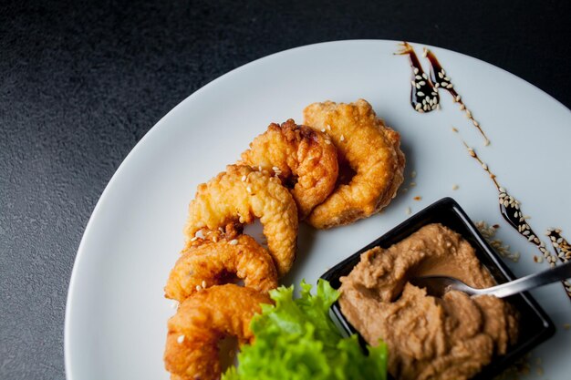 Friggere i gamberi Gamberi fritti con purè di patate con salsa su un piatto bianco