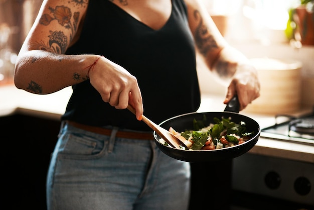 Friggere in padella la scelta sana Ritagliato colpo di una donna che prepara un pasto a casa