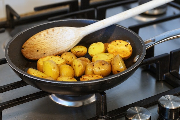 Friggere le patate novelle in una padella sul fornello.