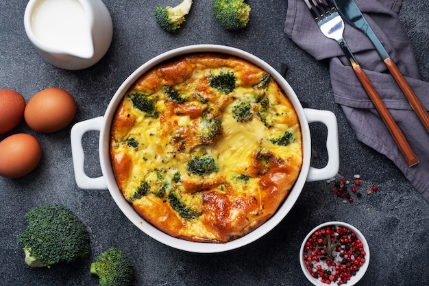 Frittata al forno con broccoli in un piatto di ceramica. Tavolo in cemento scuro. Piatto di dieta sana.