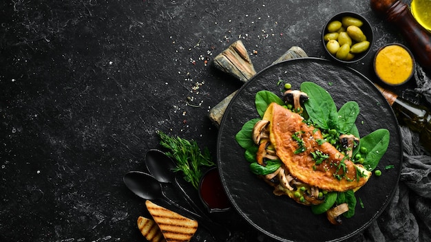 Frittata con funghi e spinaci in un piatto nero Vista dall'alto Spazio libero per il testo