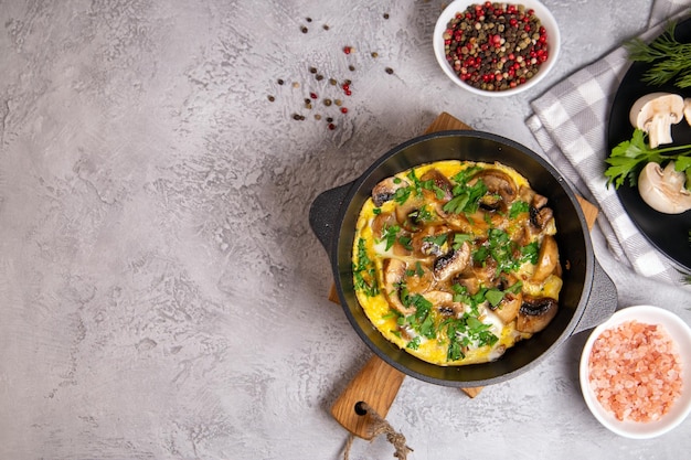 Frittata con funghi prataioli ed erbe aromatiche in padella, vista dall'alto con spazio per la copia.