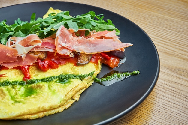 Frittata con prosciutto, salsa al pesto, rucola e peperone sulla piastra nera. Pranzo gustoso e salutare. Frittata