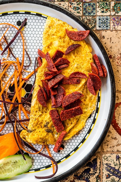 Frittata con salsiccia e verdure in piatto bianco.