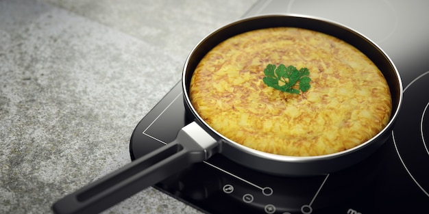 Frittata di patate appena fatta in padella. Piano di lavoro e piano cottura in vetroceramica.