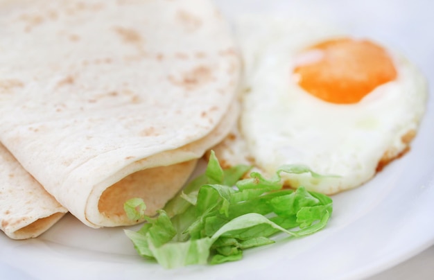 Frittata di uova con pane tortilla in un piatto come colazione sana