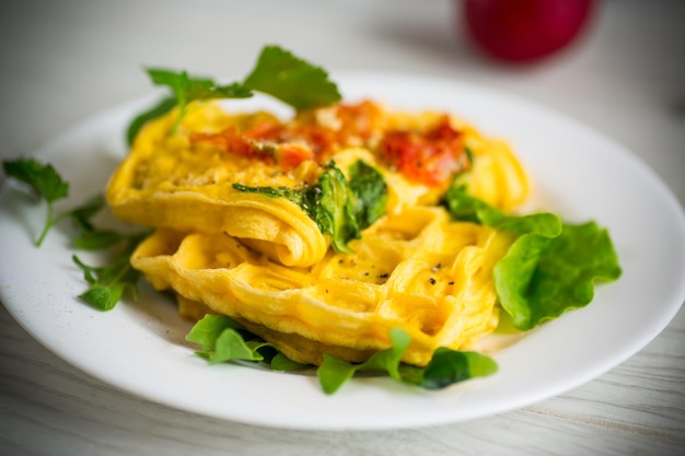 Frittata di uova ripiene di pomodoro e verdure fritte sotto forma di cialde su un tavolo di legno