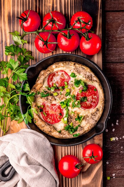 Frittata fatta in casa con pomodori ed erbe aromatiche in padella, vista dall'alto