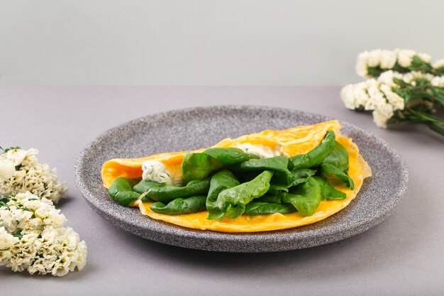 Frittata ripiena di spinaci e formaggio per una colazione con fiori in tavola foto di alta qualità