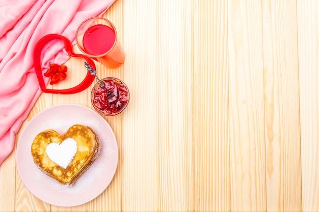 Frittelle a forma di cuore per colazione romantica con marmellata di fragole e succo di frutta