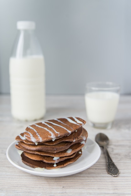 Frittelle al cioccolato con il bicchiere e la bottiglia di latte