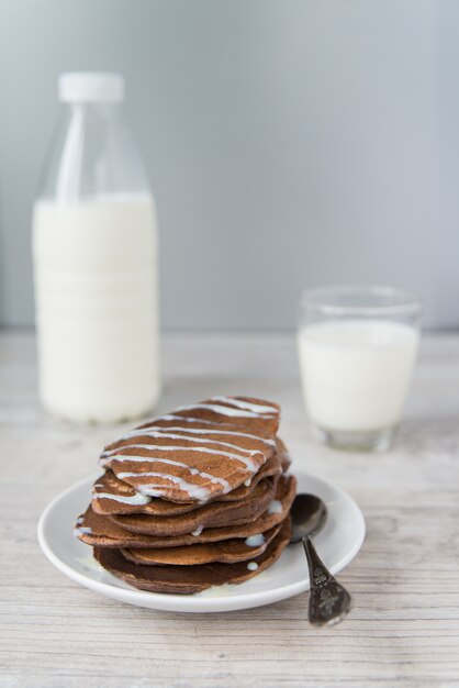 Frittelle al cioccolato con il bicchiere e la bottiglia di latte