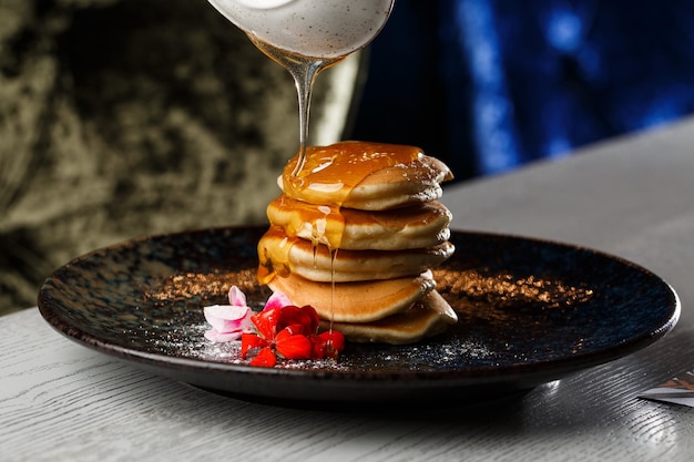 Frittelle americane con frutti di bosco e sciroppo d'acero su piatto nero isolato su sfondo scuro Menu del caffè