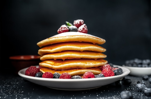 Frittelle americane con lamponi, mirtilli freschi e miele. Sana colazione su cemento