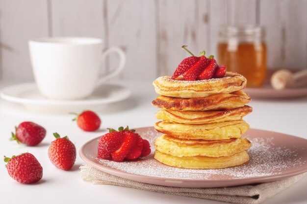 Frittelle appena sfornate con fragole su uno sfondo di legno naturale