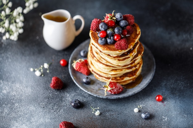 Frittelle con frutti di bosco e sciroppo d'acero. Dolce pila fatta in casa di frittelle