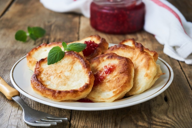 Frittelle con marmellata di lamponi su un piatto bianco