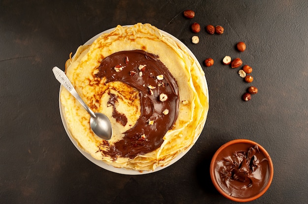 Frittelle con pasta di cioccolato e nocciole, su un piatto bianco su uno sfondo di cemento, ardesia con copia spazio per il testo