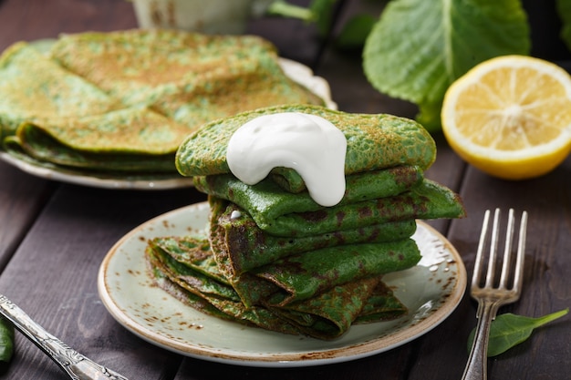 Frittelle con spinaci e panna acida sul tavolo di legno.