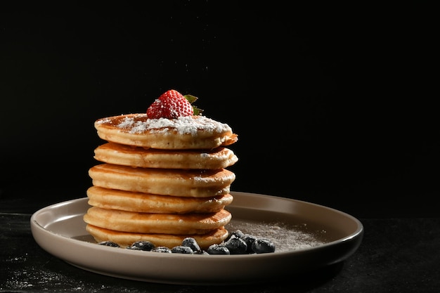 frittelle con zucchero, fragole e mirtilli su una consistenza scura.