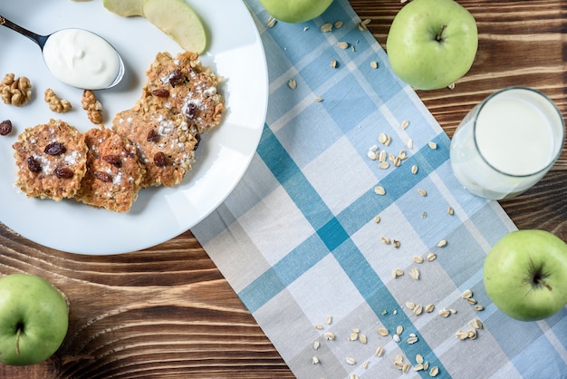 Frittelle di avena fatte in casa con yogurt vegano, uvetta e noci sul tavolo di legno con tessuto blu nella scatola.