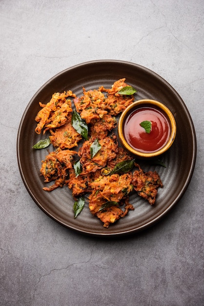 Frittelle di carote o Gajar ke pakore o pakode o bajji o bhaji, snack indiano servito in un piatto con ketchup