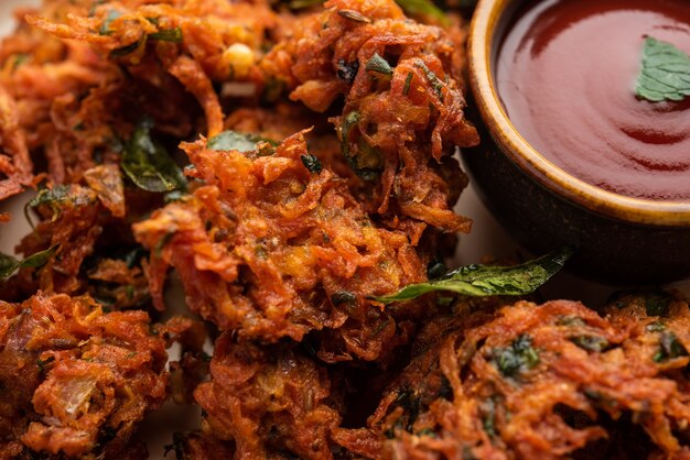 Frittelle di carote o Gajar ke pakore o pakode o bajji o bhaji, snack indiano servito in un piatto con ketchup