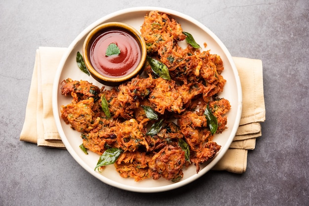 Frittelle di carote o Gajar ke pakore o pakode o bajji o bhaji, snack indiano servito in un piatto con ketchup