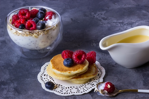 Frittelle di farina di riso e budino di chia con farina d'avena, lamponi e mirtilli su un grigio