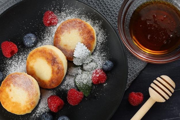 Frittelle di formaggio fatto in casa con frutti di bosco freschi e miele